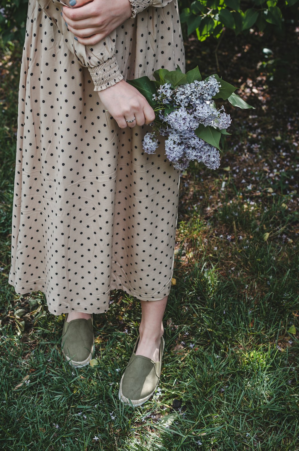 Frau in weiß-schwarzem Polka-Dot-Kleid und weißen Schuhen auf grünem Rasenfeld