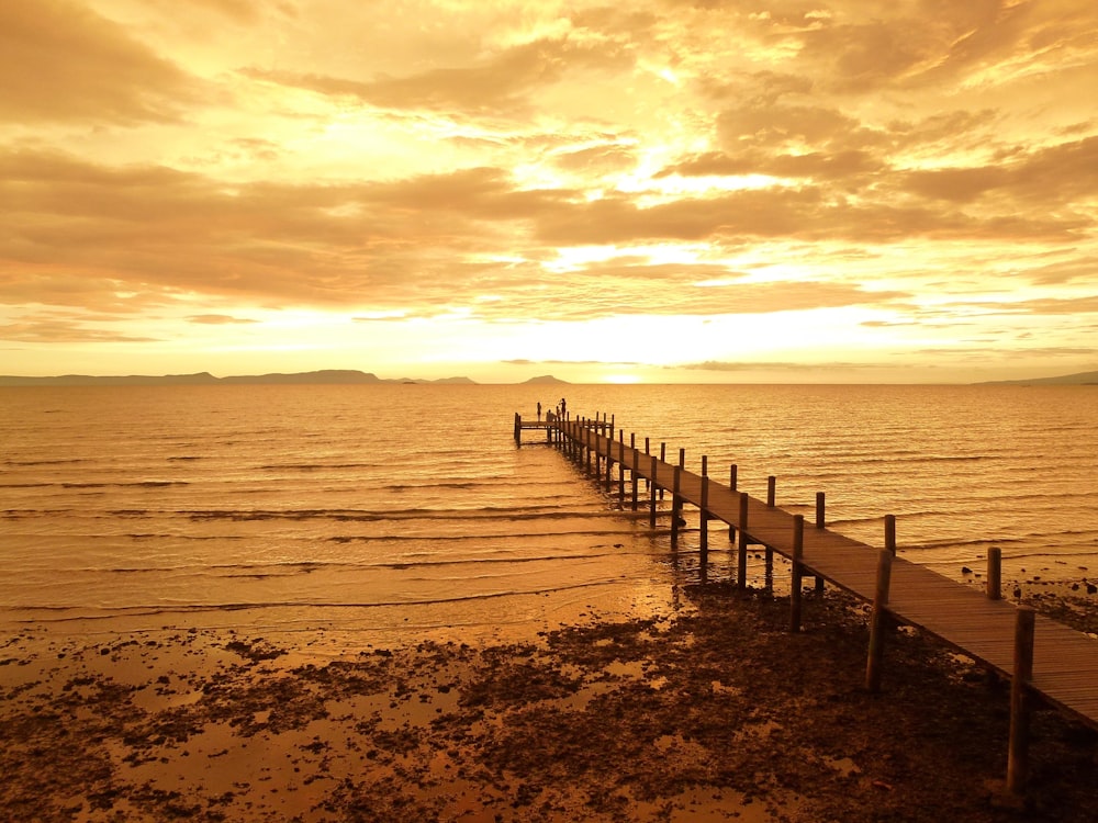 brown wooden dock on sea during sunset