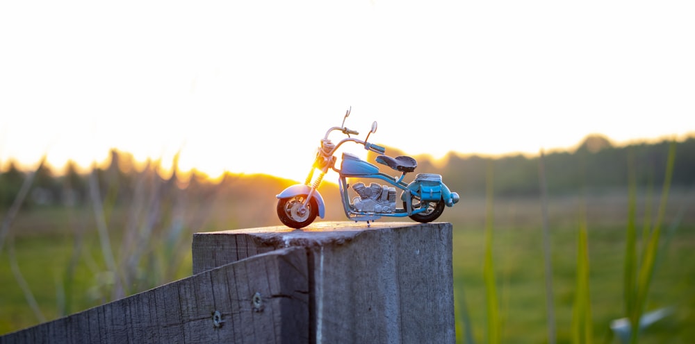 juguete de motocicleta amarillo y negro en cerca de madera marrón durante el día