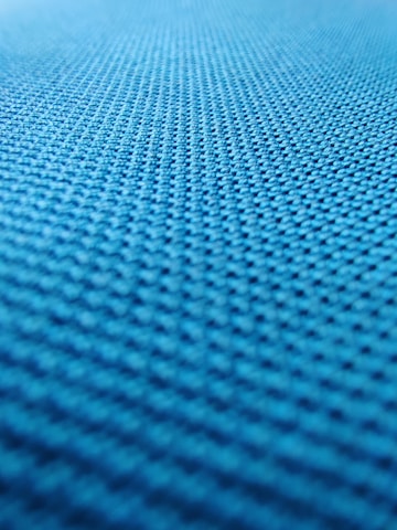 A close-up view of a textured surface with a repeating pattern, likely a fabric or material with a woven or mesh-like structure. The texture appears to be uniform and consists of small, evenly distributed bumps or nodes.