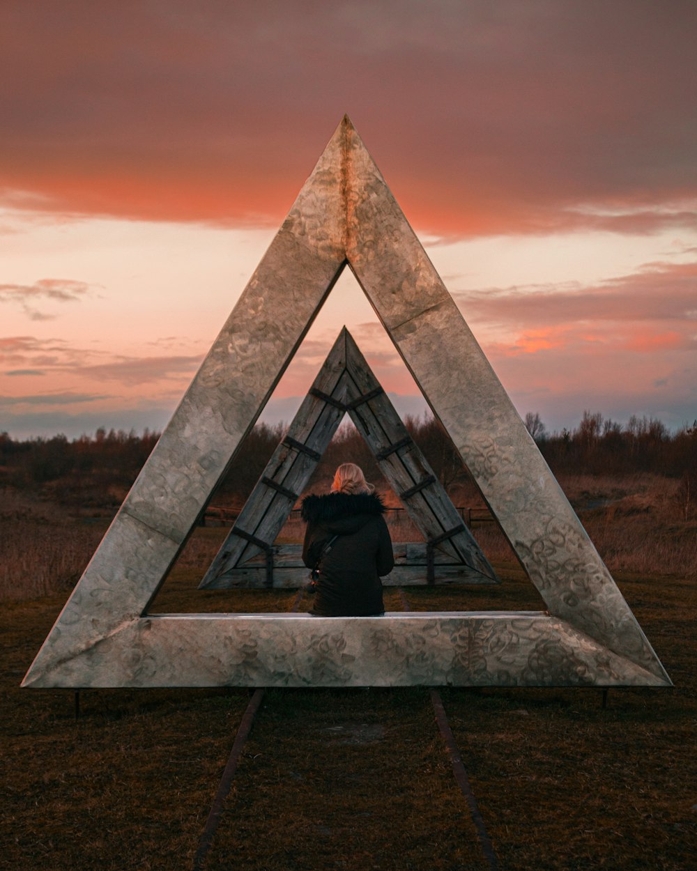 personne assise sur le bord de la pyramide au coucher du soleil