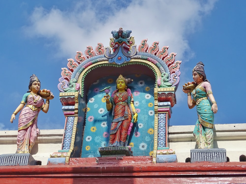 man in green shirt and blue denim jeans standing in front of hindu deity statue