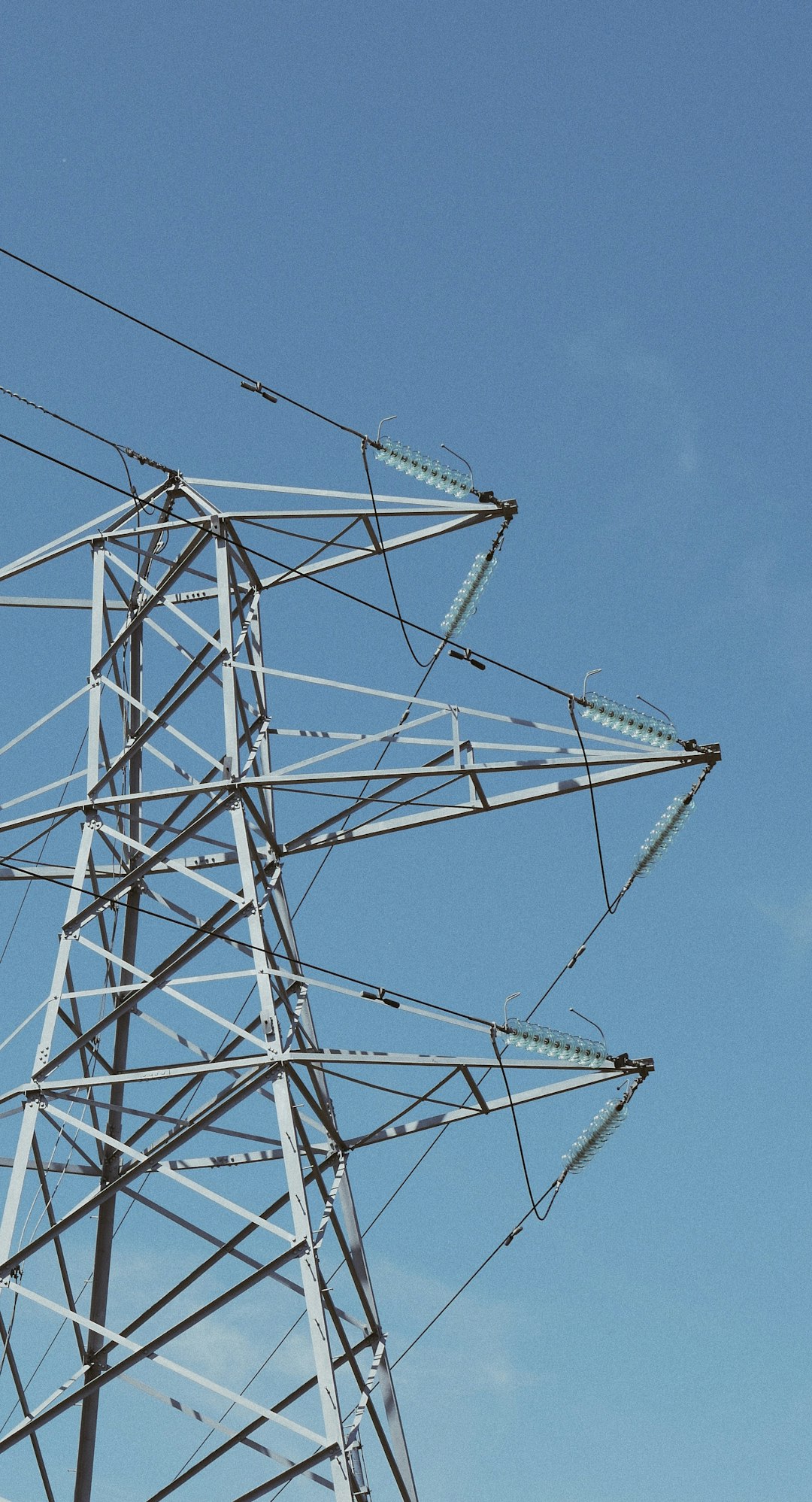  white metal electric towers under blue sky during daytime wire