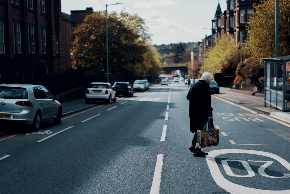 woman in black coat walking on the street during daytime