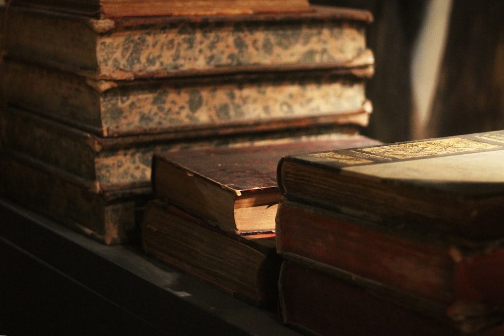 brown hardbound books on black wooden table