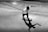 grayscale photo of man in white t-shirt and black pants doing skateboard stunts