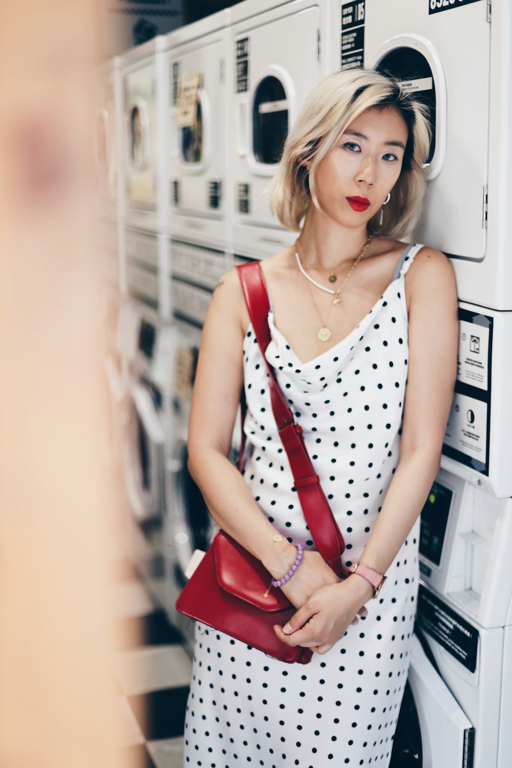 woman in white and black polka dot tank top and red pants sitting on white plastic