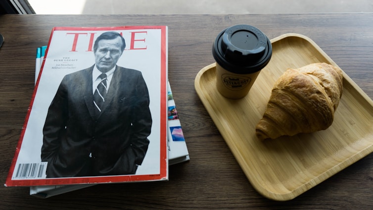 A sleek obsidian black matte gold embossed magazine cover resting on a glass boardroom table.
