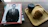 A magazine with a black and white cover featuring a man in a suit is placed on a wooden table. Next to it, there is a wooden tray with a takeaway coffee cup and a croissant.