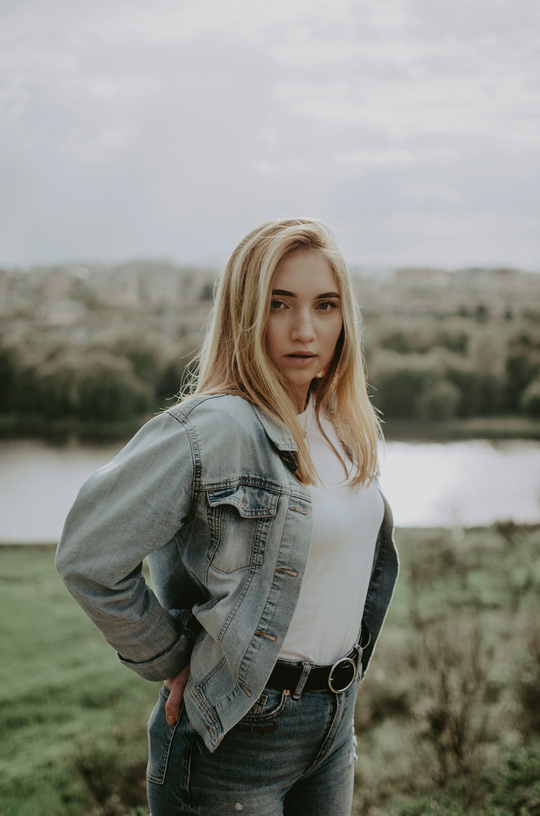 woman in blue denim jacket standing on green grass field during daytime