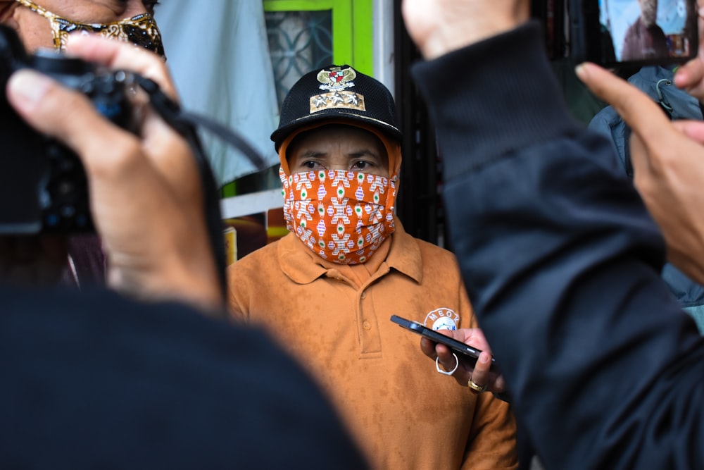 man in orange polo shirt wearing black and white hat