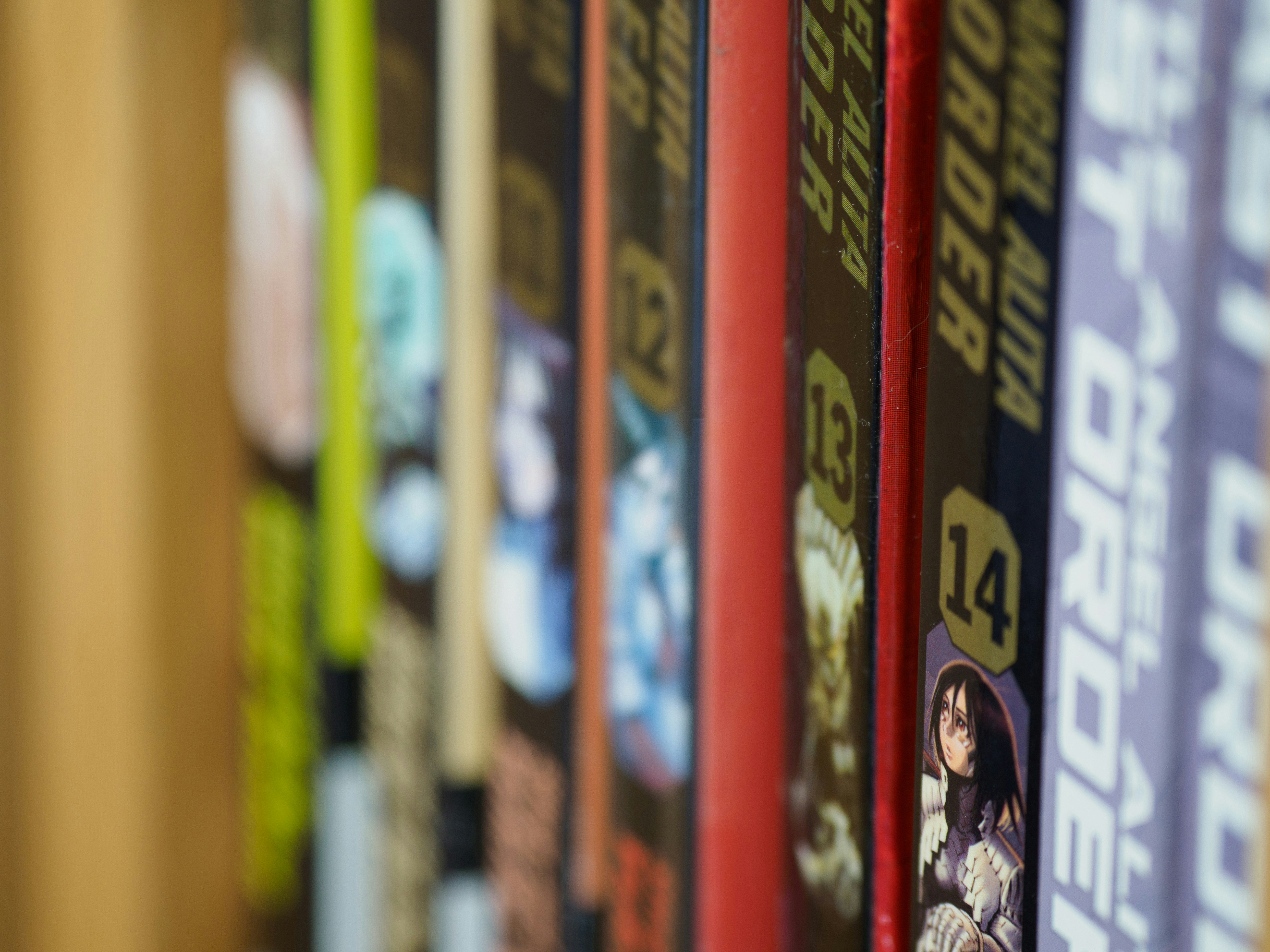 close up, bokeh, macro, blur, blurred background, close focus, alita, alita manga, alita book, alita graphic novel, book, book spines, book spine, manga, 