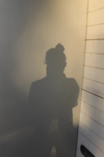 Soft shadows cast on a white wall as a student holds a gentle stretch.