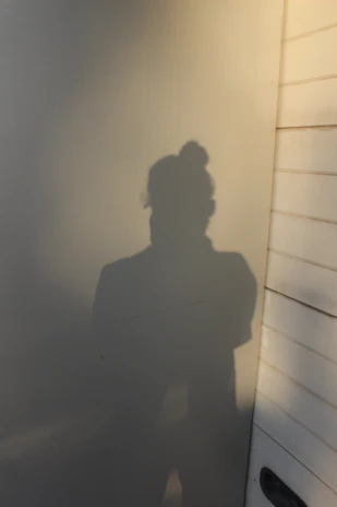 Soft shadows cast on a white wall as a student holds a gentle stretch.