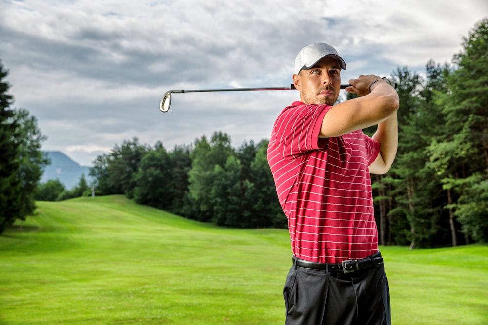 man in red and white plaid shirt and black pants holding golf club