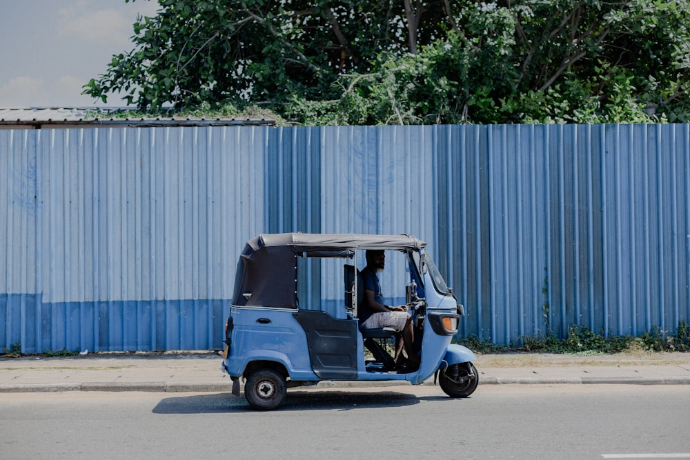 blue and white auto rickshaw parked beside white wall