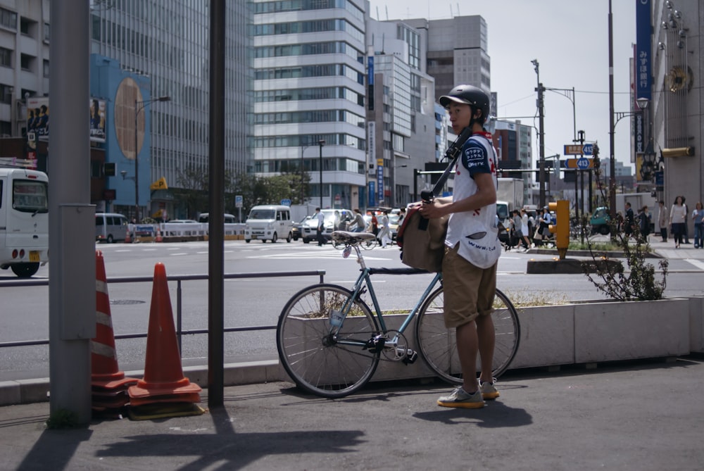 白いTシャツと黒い短パンを着た男が昼間、道路を黒い自転車で走る