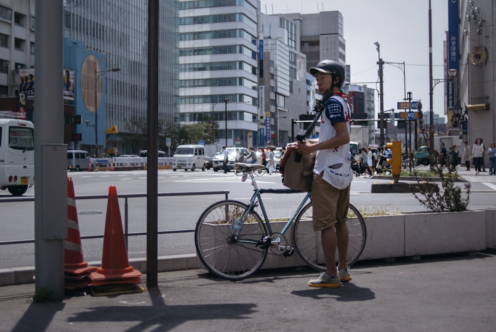 man in white t-shirt and black shorts riding on black bicycle on road during daytime