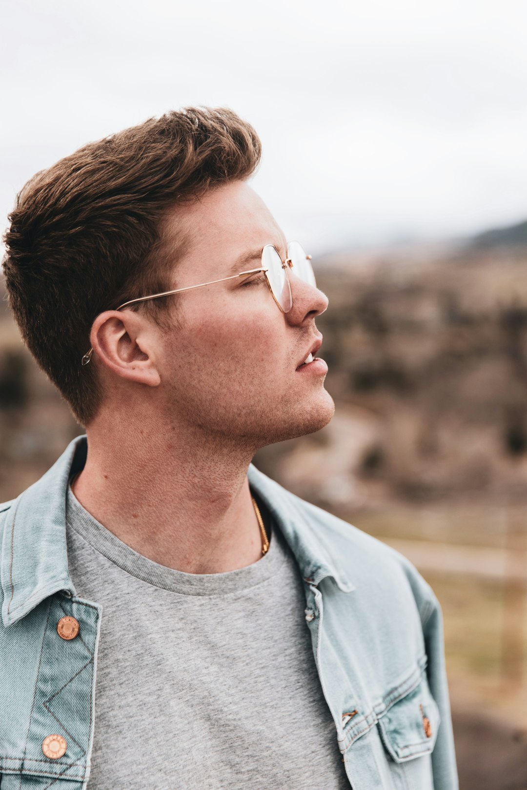 man in blue denim button up shirt wearing white framed eyeglasses