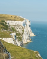 white and green mountain beside blue sea during daytime