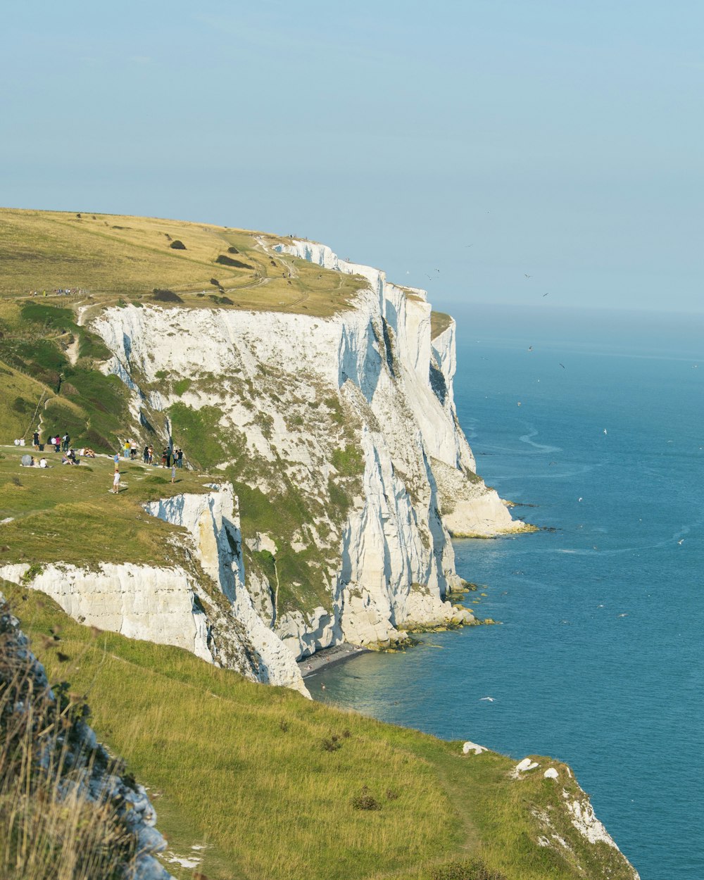 white and green mountain beside blue sea during daytime