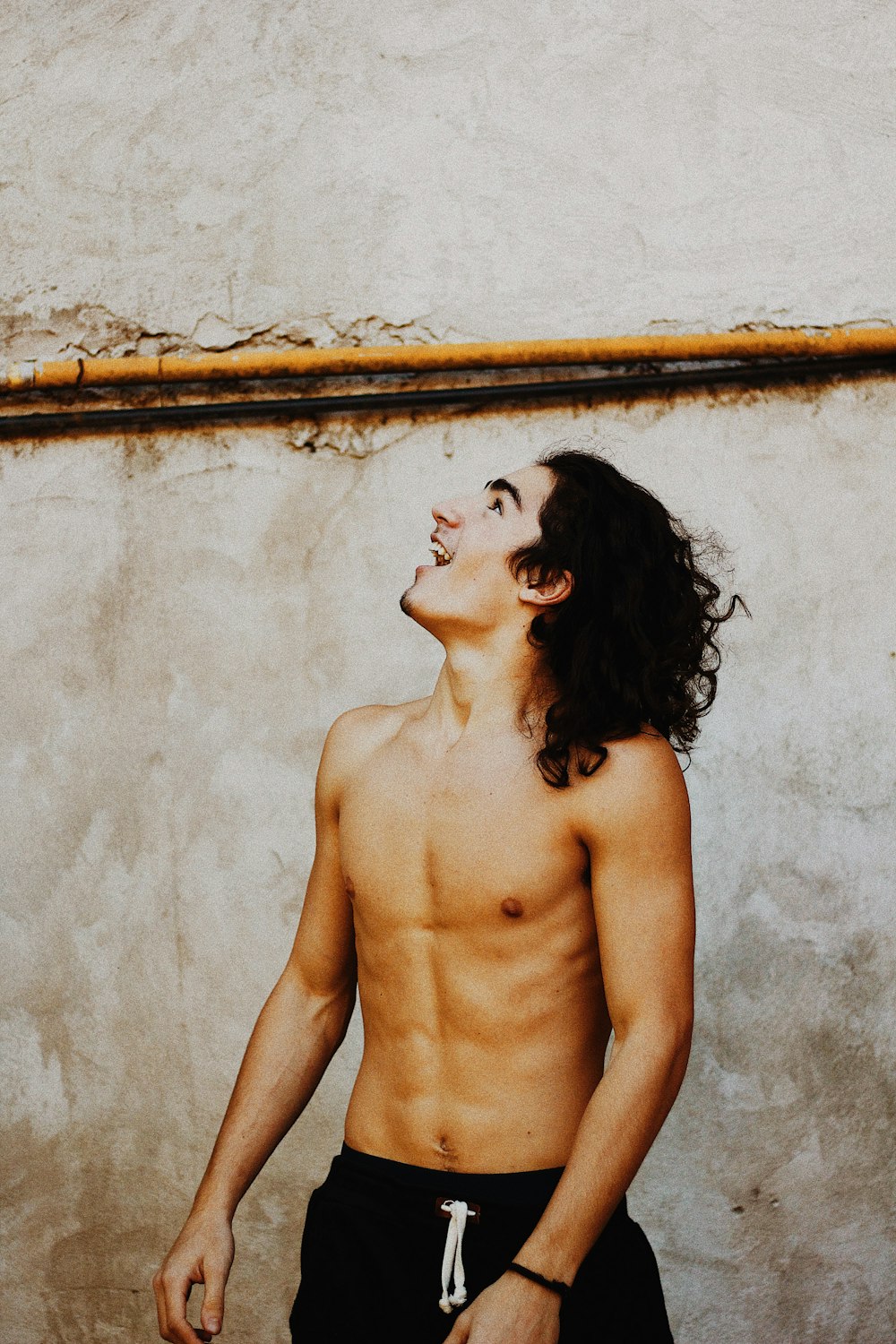 topless woman leaning on white wall