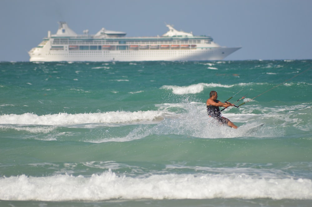 Hombre con traje de neopreno naranja y negro surfeando sobre las olas del mar durante el día