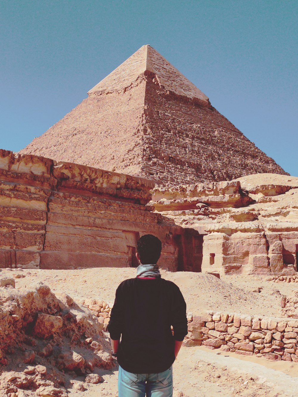 man in black jacket standing in front of pyramid during daytime