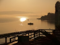 A serene lakeside view with a small boat drifting by at golden hour.