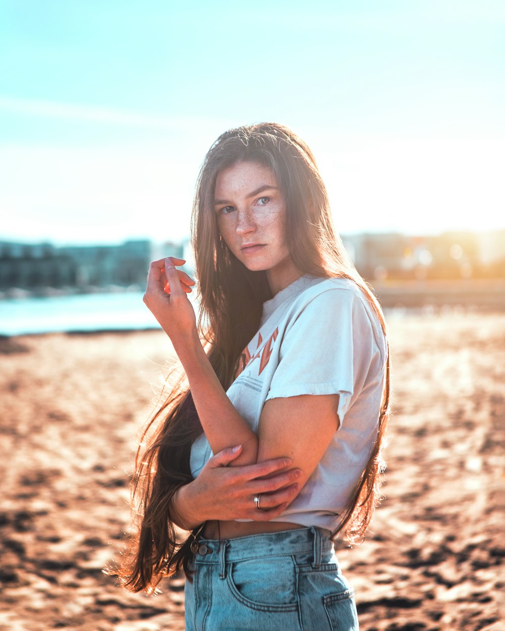 woman in white shirt and blue denim jeans standing on brown field during daytime