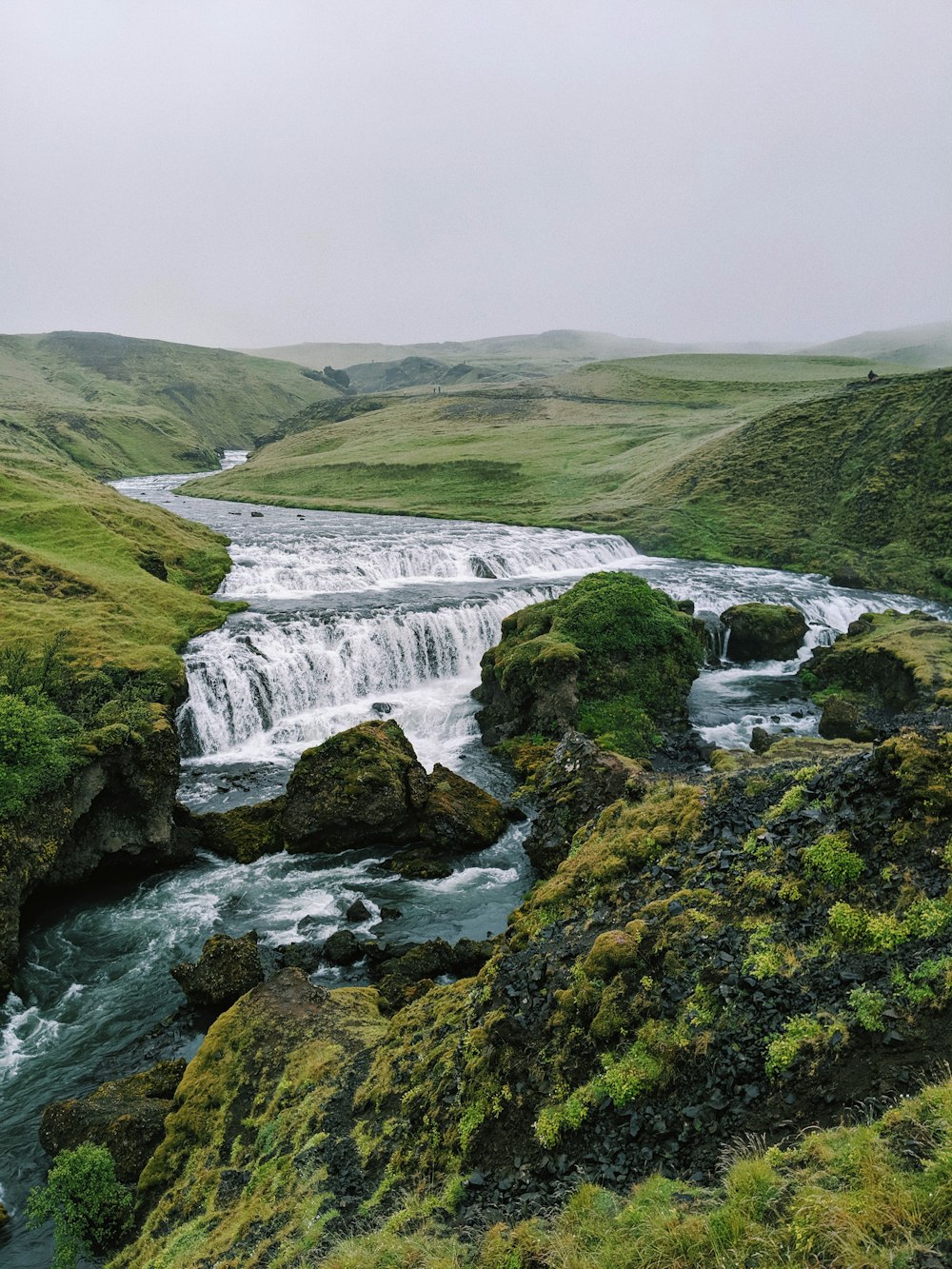 waterfalls on green grass covered hill during daytime