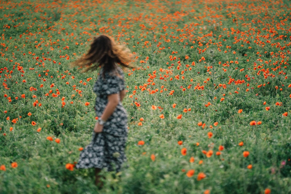 girl in black and white dress standing on flower field during daytime