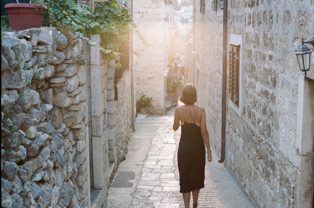 woman in black dress walking on pathway during daytime