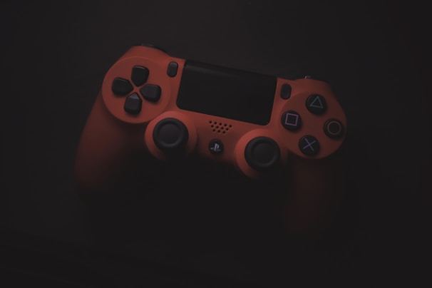 A red gaming controller with various buttons and joysticks is placed against a dark background, highlighting its features.