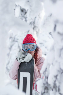 A stylish winter ski outfit laid out on fresh snow, featuring a light grey jacket, soft gloves, and a knitted hat.