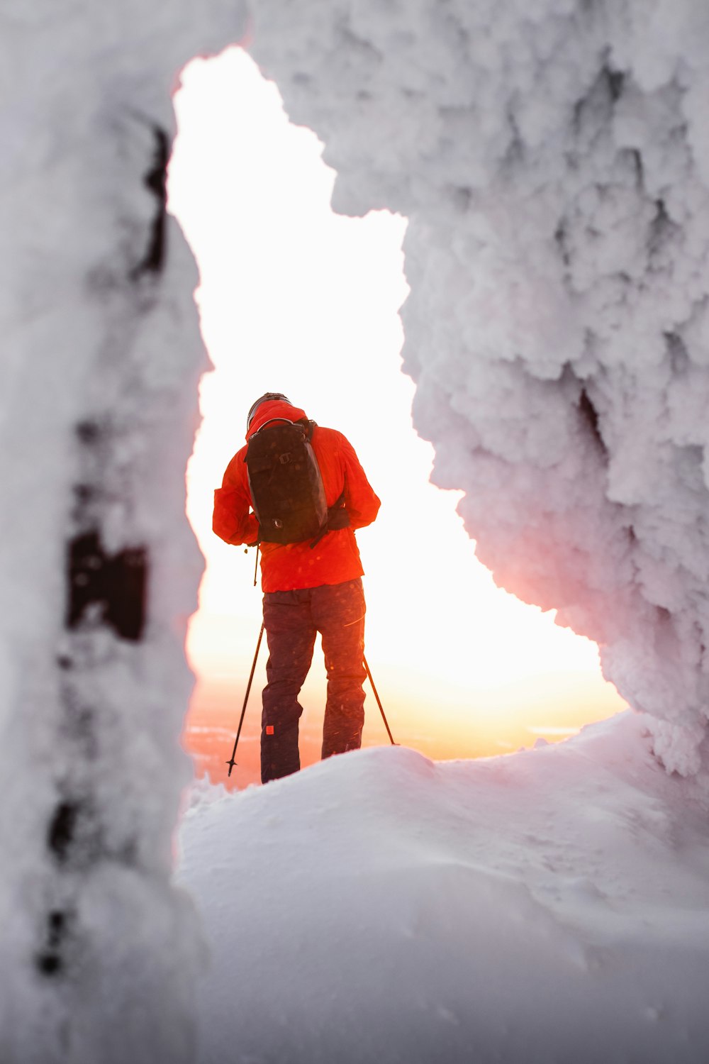 person in red jacket and black pants standing on snow covered ground during daytime