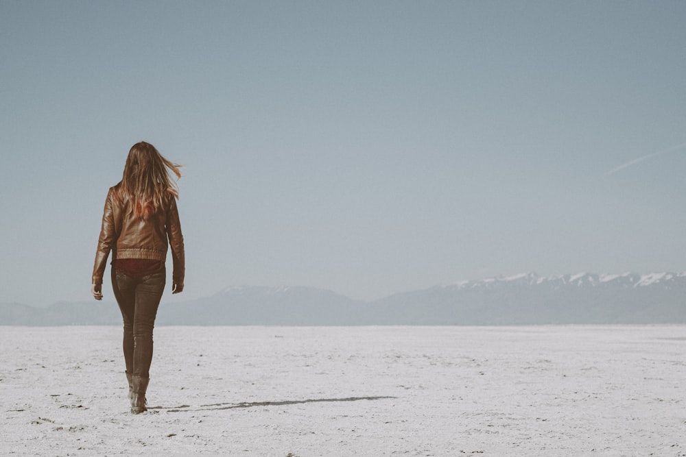 woman in brown jacket standing on white snow covered field during daytime