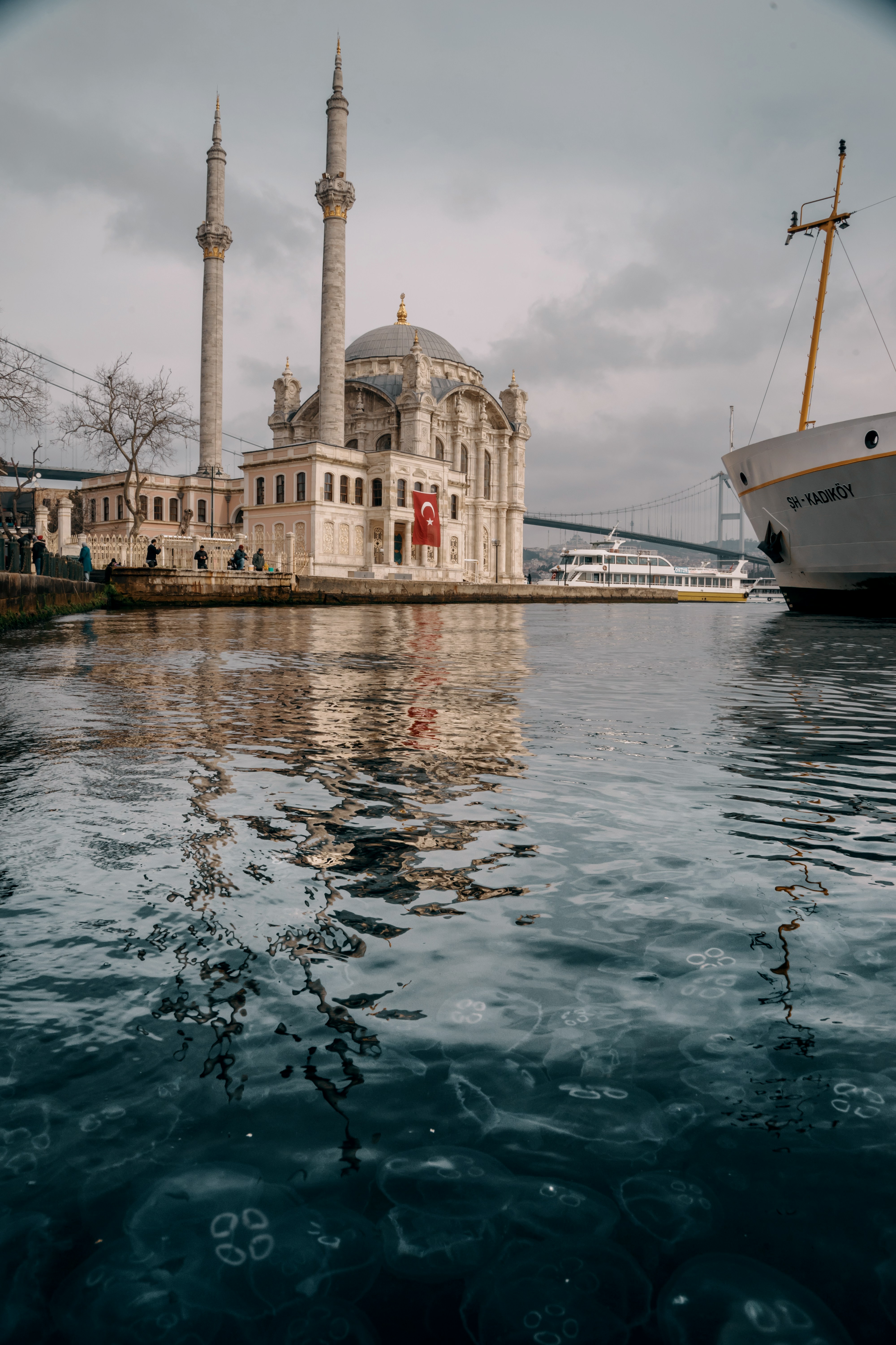 white and brown boat on water near white concrete building during daytime