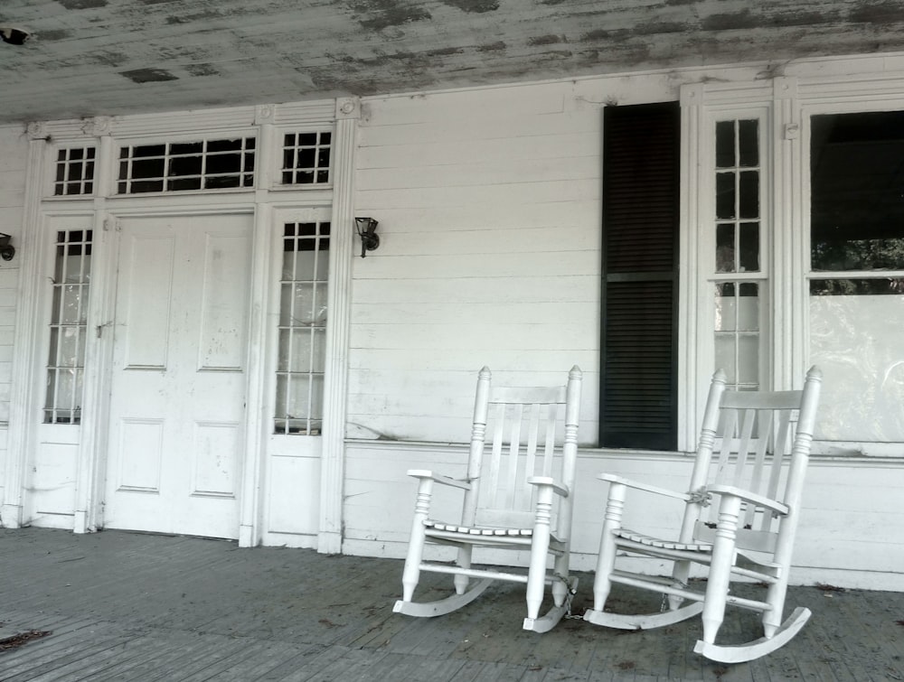 sedia a dondolo in legno bianco accanto alla porta in legno bianco