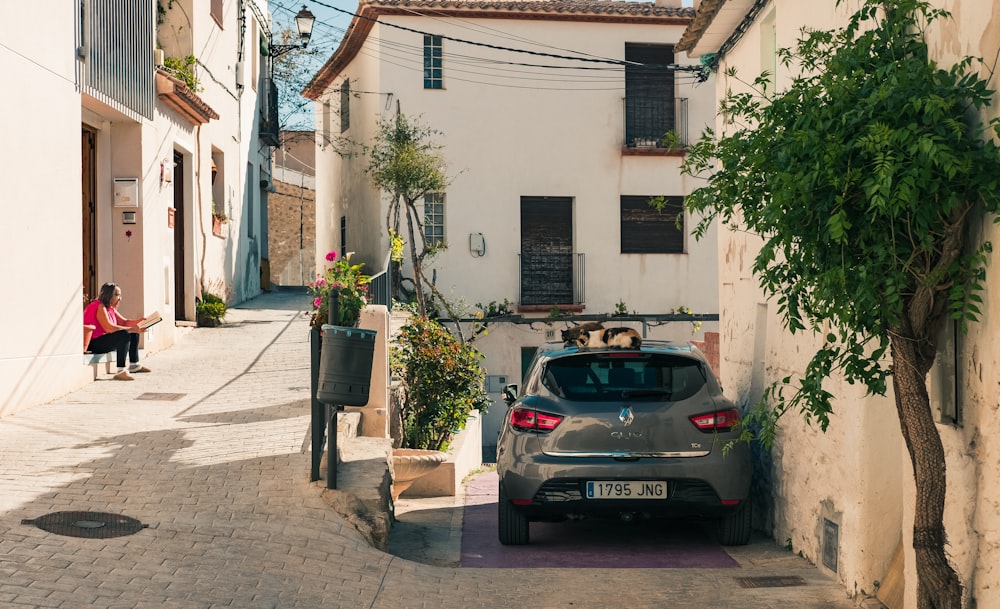 black sedan parked beside white concrete building during daytime