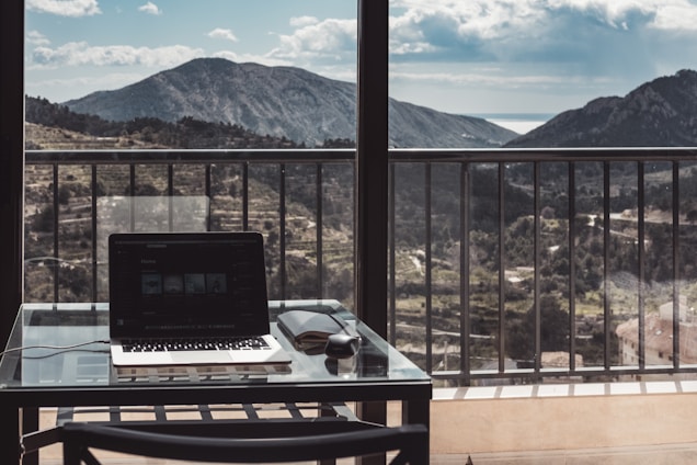 A friendly freelancer working on a laptop with Swiss mountains visible through the window.