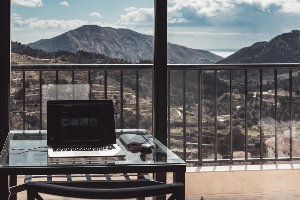 Laptop on a wooden table by a window