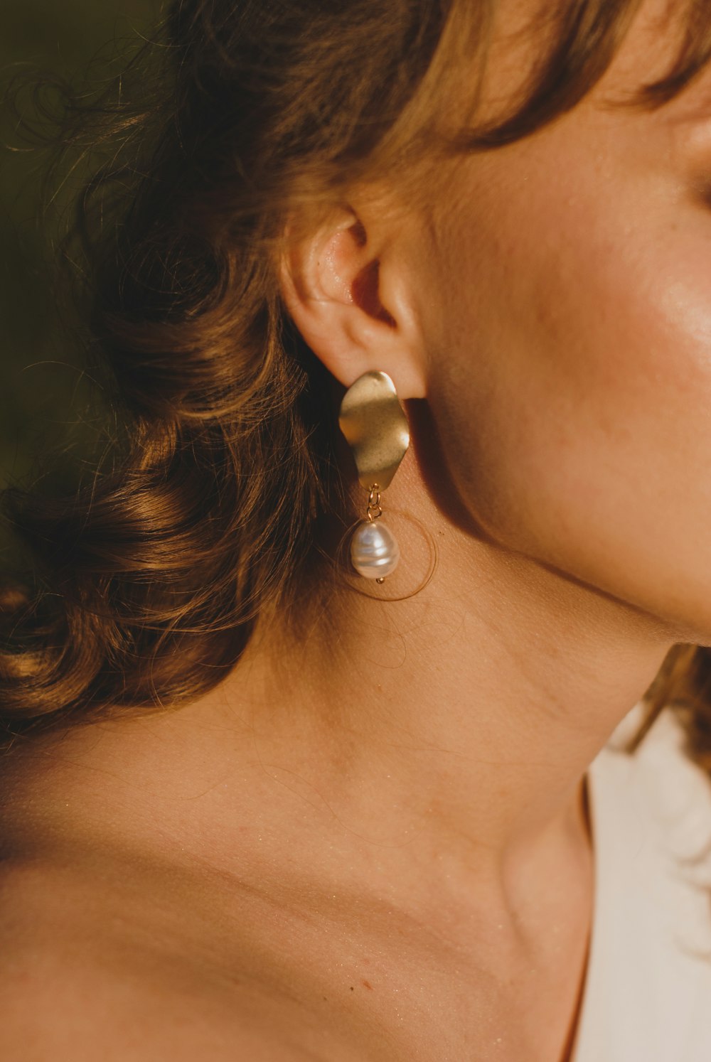 Femme portant une boucle d’oreille en perle argentée et blanche