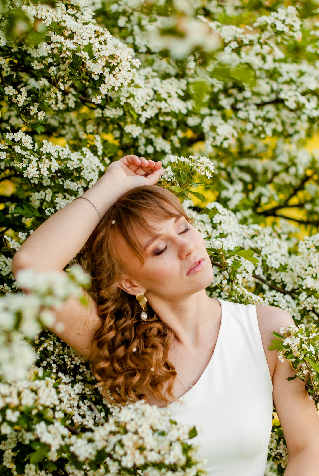 woman in white tank top holding yellow flowers