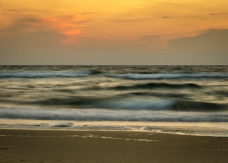A serene ocean wave gently rolling onto a quiet beach at sunset, evoking calm and relaxation.