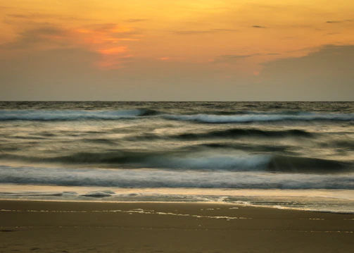 The slow, rhythmic movement of ocean tides under a golden sunset.