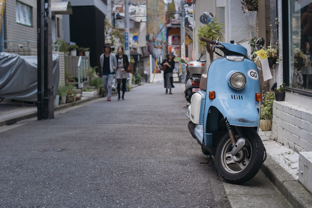 scooter azul e branco estacionado na calçada durante o dia