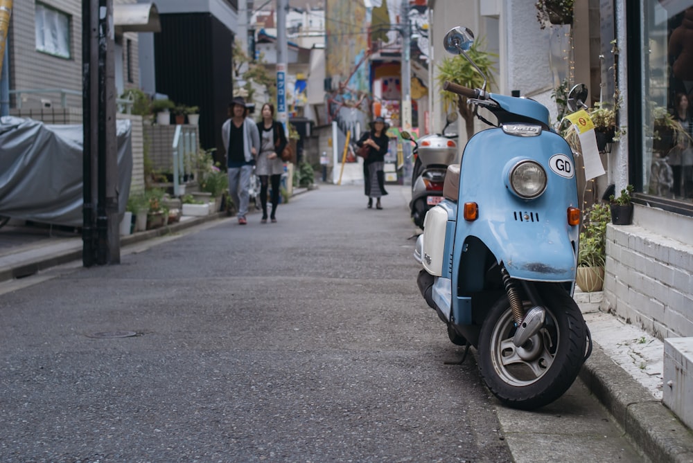 blue and white motor scooter parked on sidewalk during daytime