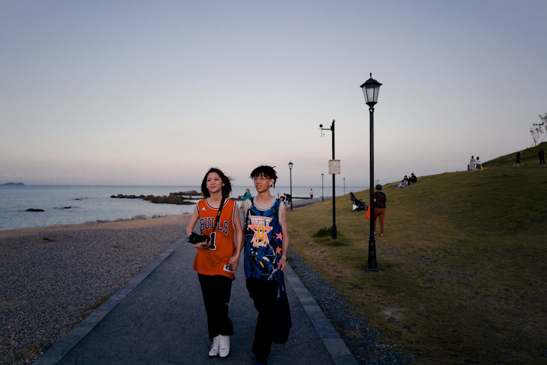 woman in orange jacket standing on gray concrete road during daytime