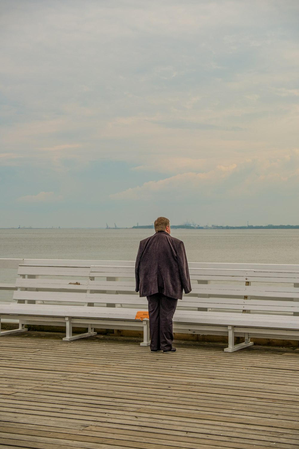 man in gray coat standing on white wooden dock during daytime